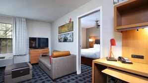 A hotel room with a sofa, a desk, a television, a bed, and a bathroom visible through an open door. - TownePlace Suites by Marriott Tucson (Tucson)