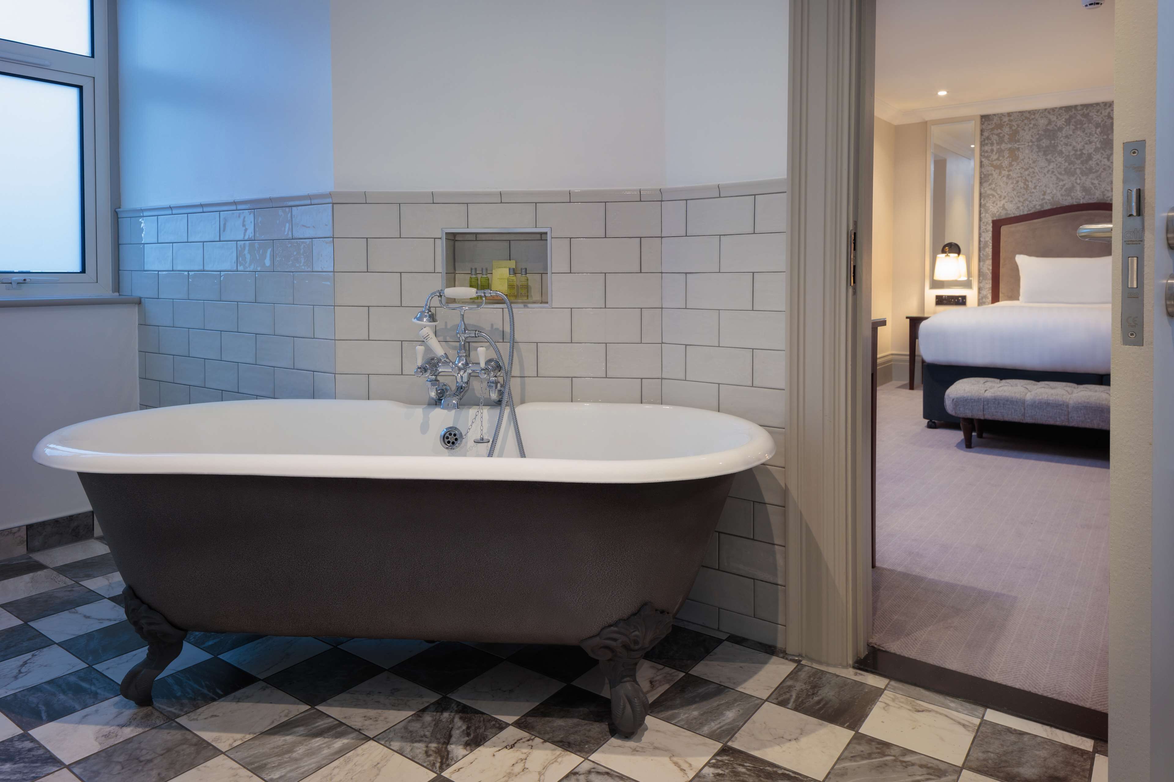 A modern bathroom with a freestanding bathtub, a mirror, and a small shelf with toiletries.