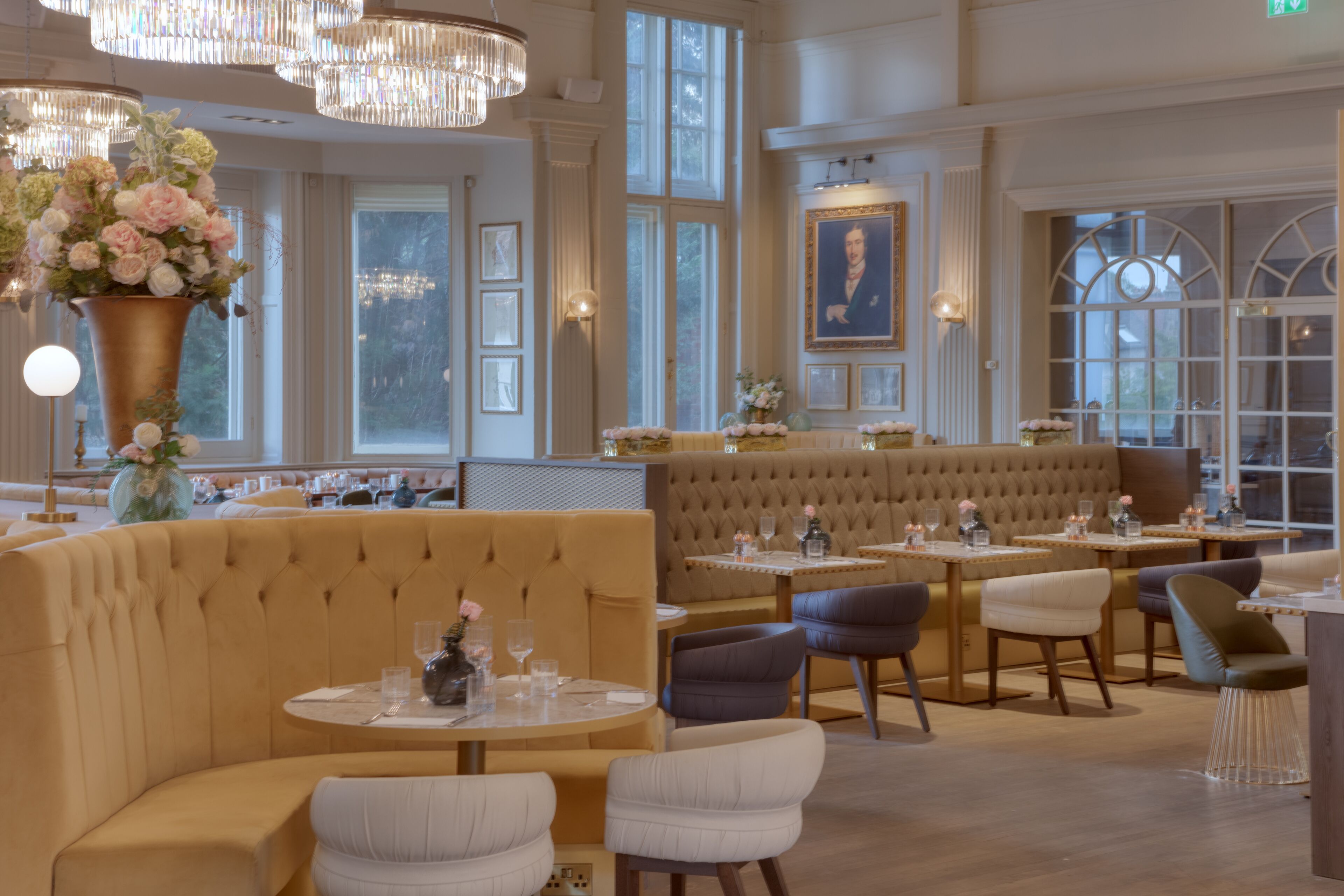 Un restaurante con mesas redondas, asientos acolchados y candelabros.
