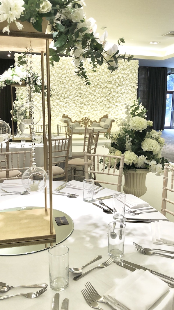 Un comedor con mesas redondas, sillas y un fondo floral.