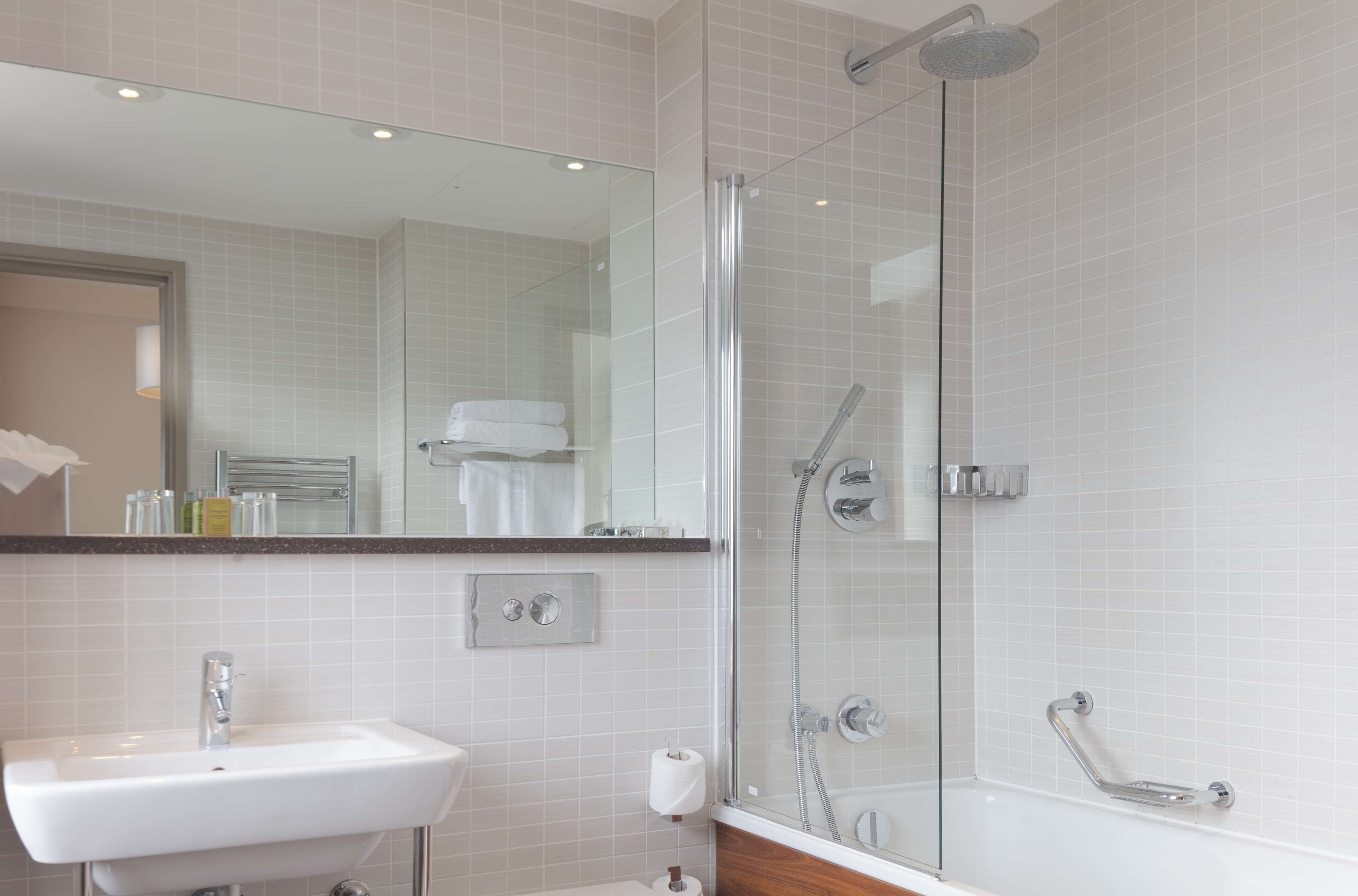A modern bathroom with a glass-enclosed shower, a sink, and a mirror.