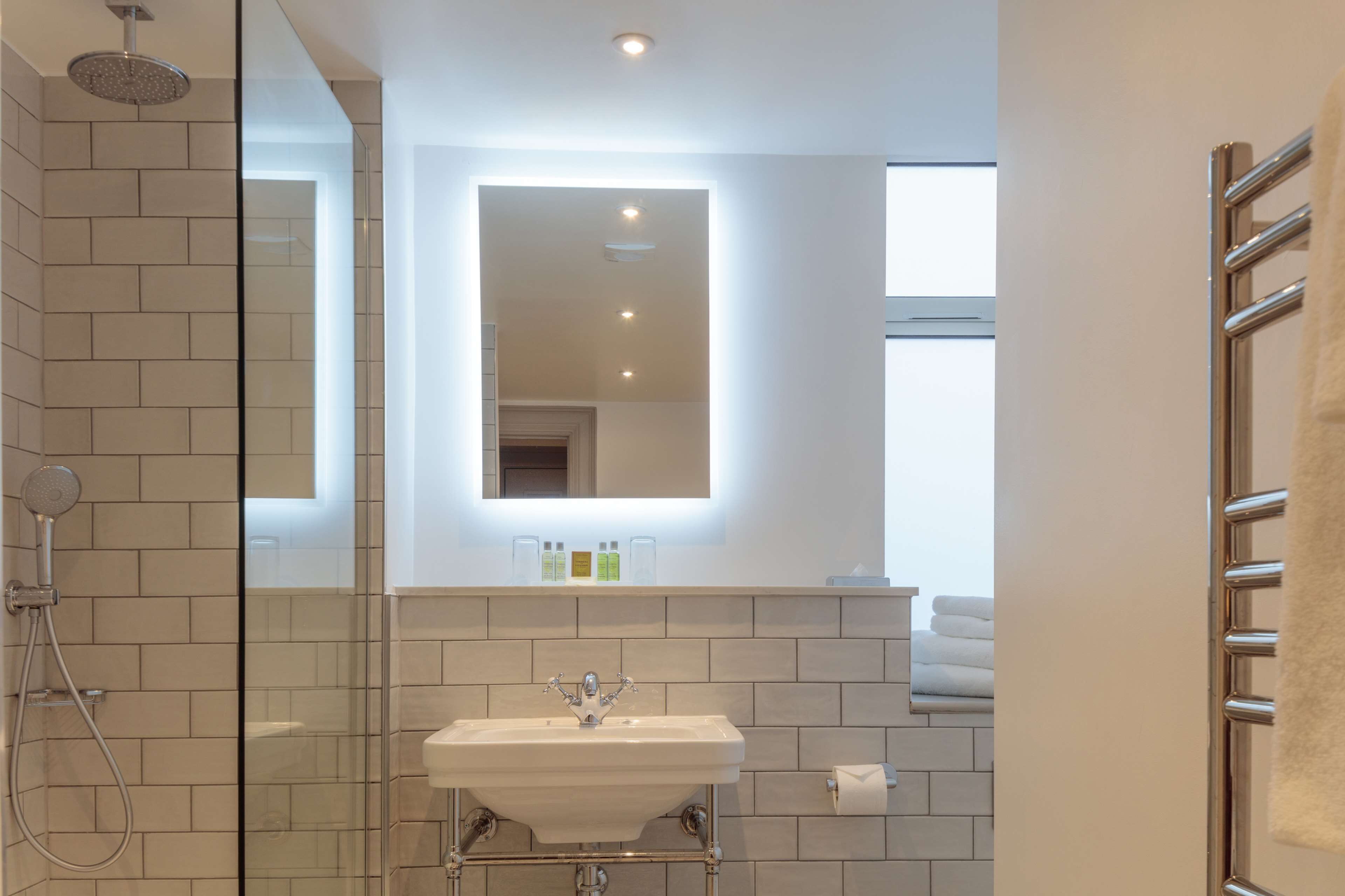 A modern bathroom with a glass shower enclosure, a white sink, and a mirror above it.