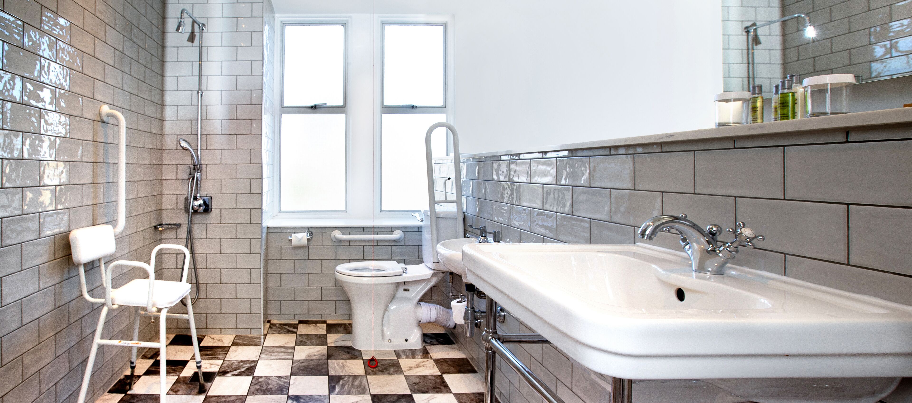 A modern bathroom with a checkered floor, a white toilet, a white sink, and a shower.