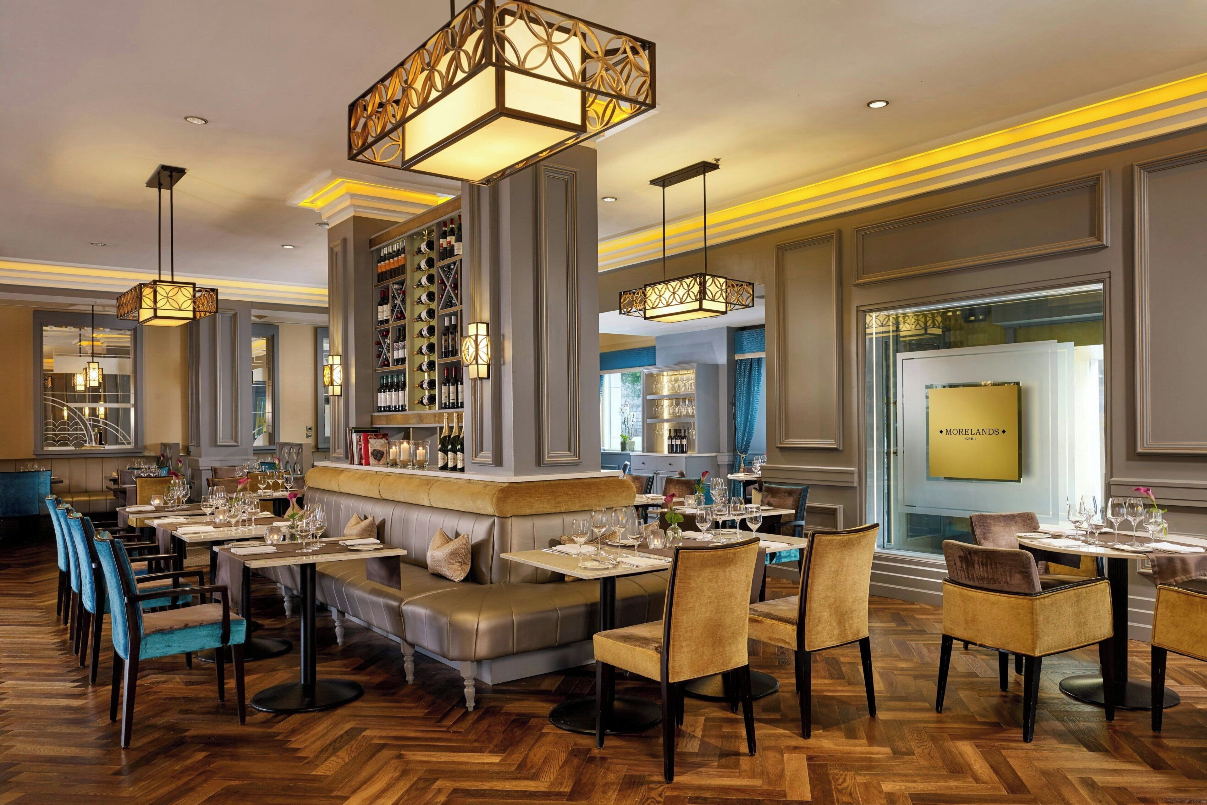 Un restaurant doté d’un plancher en bois, de tables dressées pour le service et de luminaires suspendus.