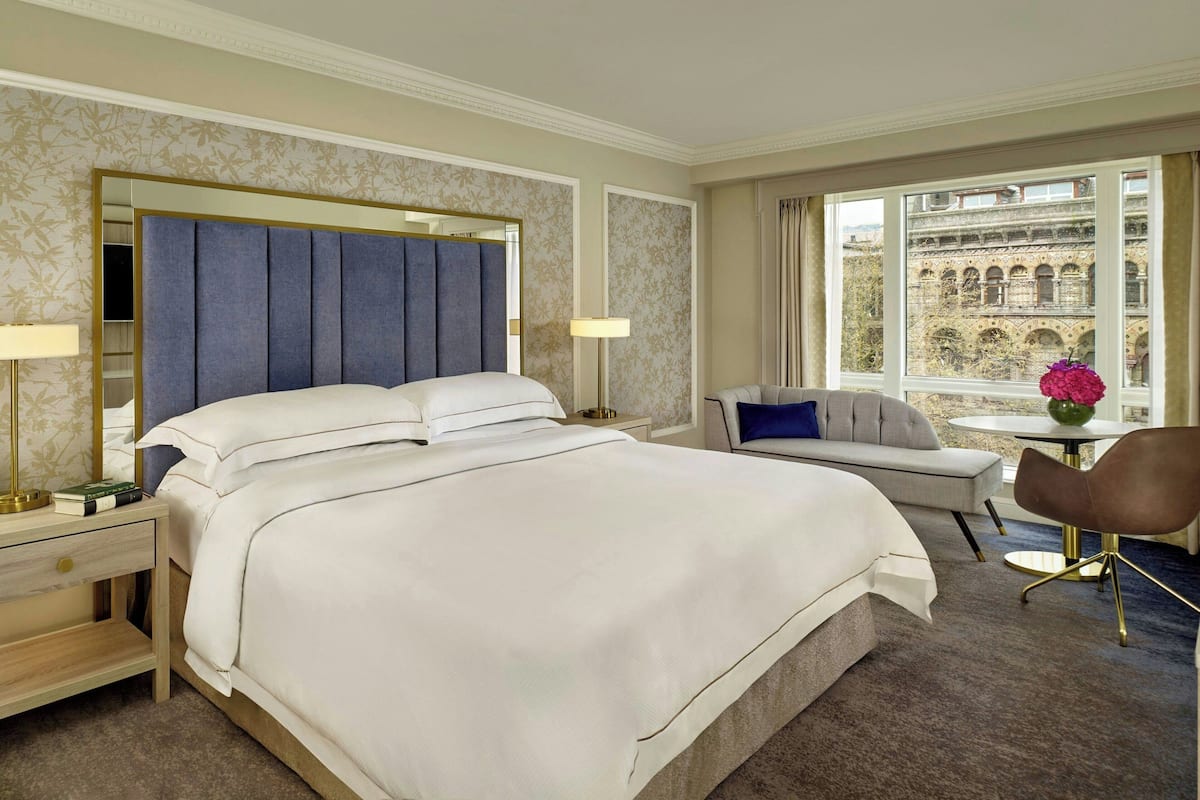 Una habitación de hotel con una cama grande, un sofá, una silla y una mesita.