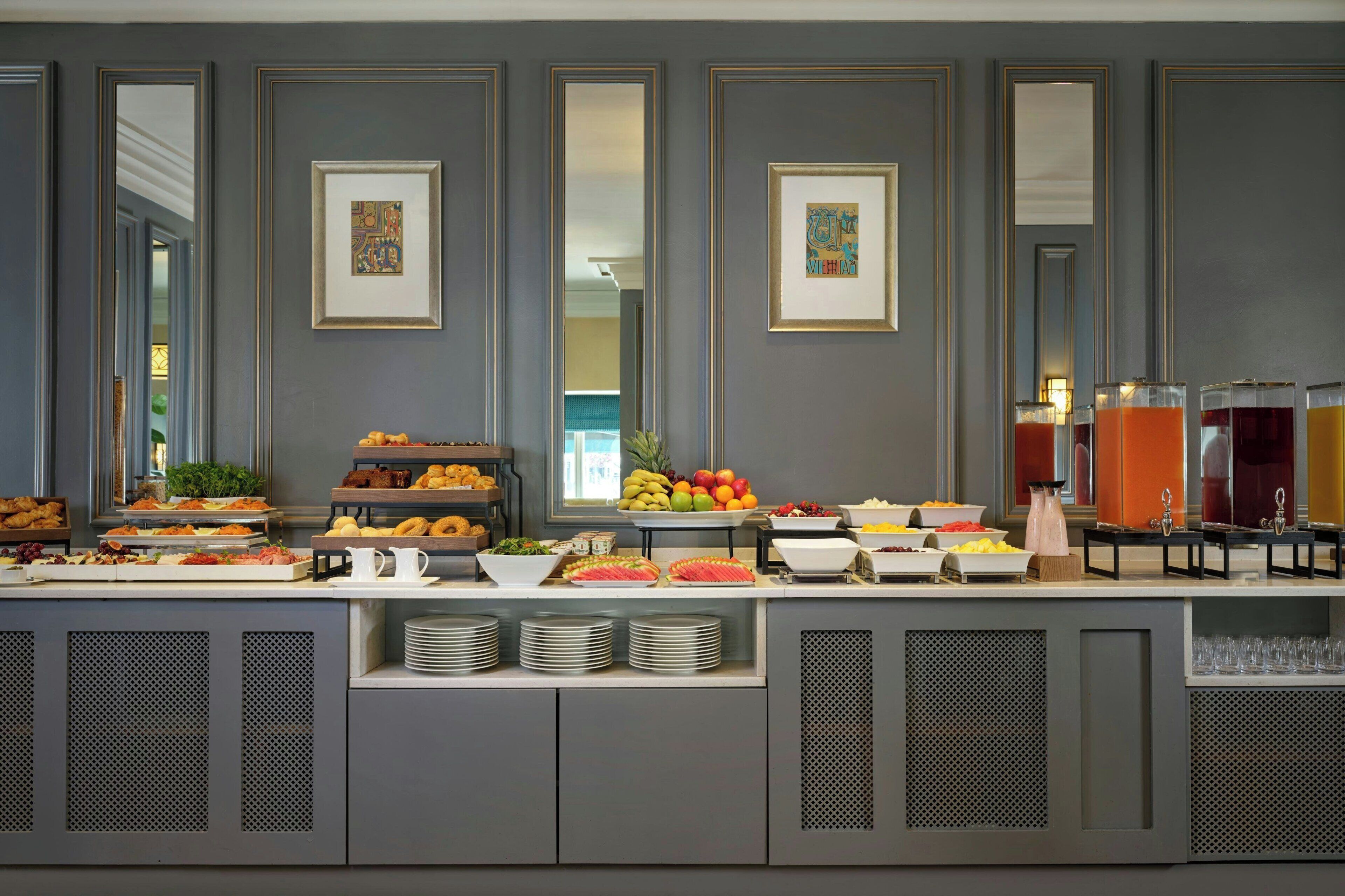 A buffet with various food items and beverages, framed artwork on the wall, and a modern design.