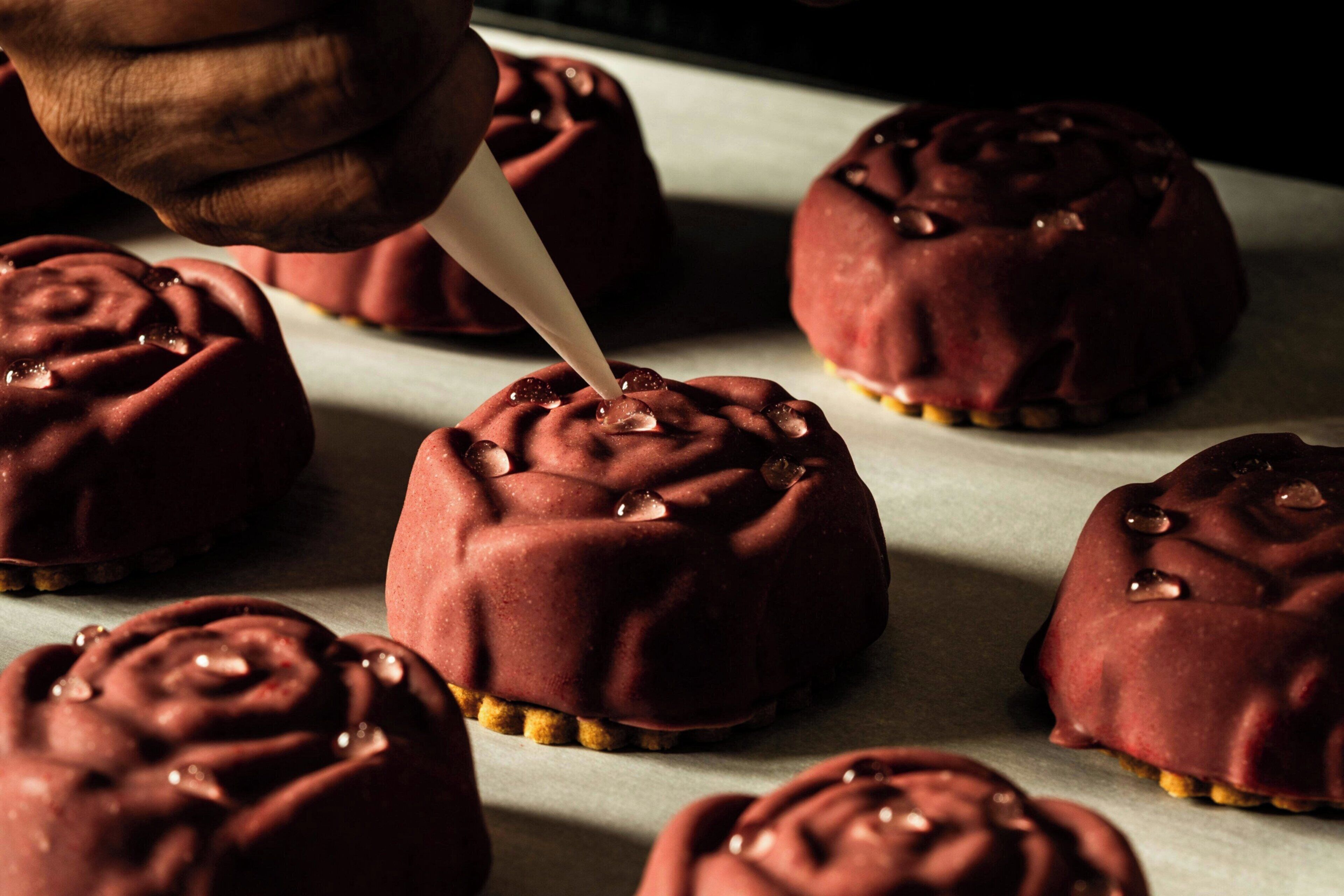 Una mano cubriendo un pastel con cobertura de chocolate.