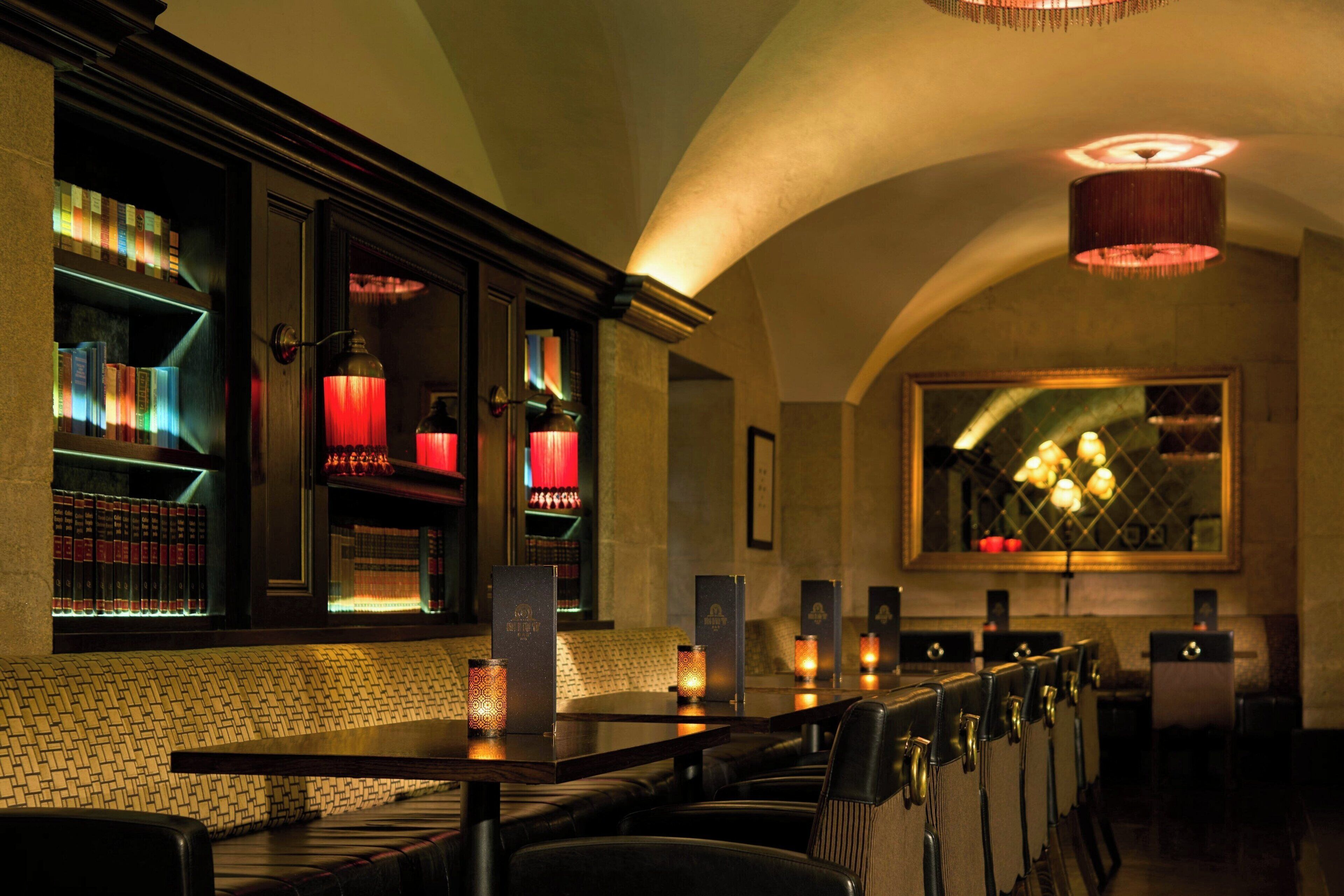 A bar area with bookshelves, a seating area, and a large mirror.
