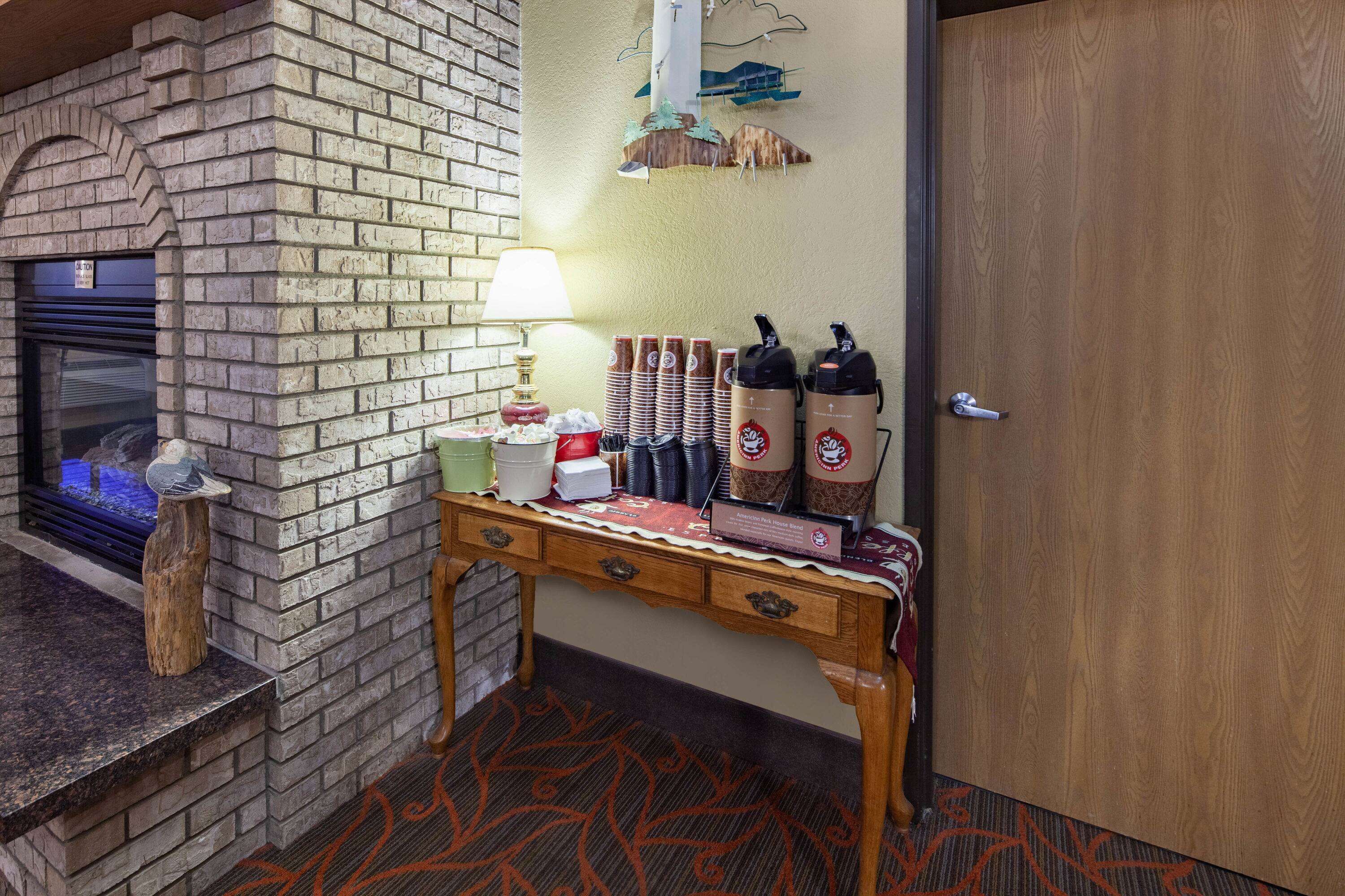 A brick fireplace with a glass door, a wooden table with a placemat, and a door with a wooden panel.