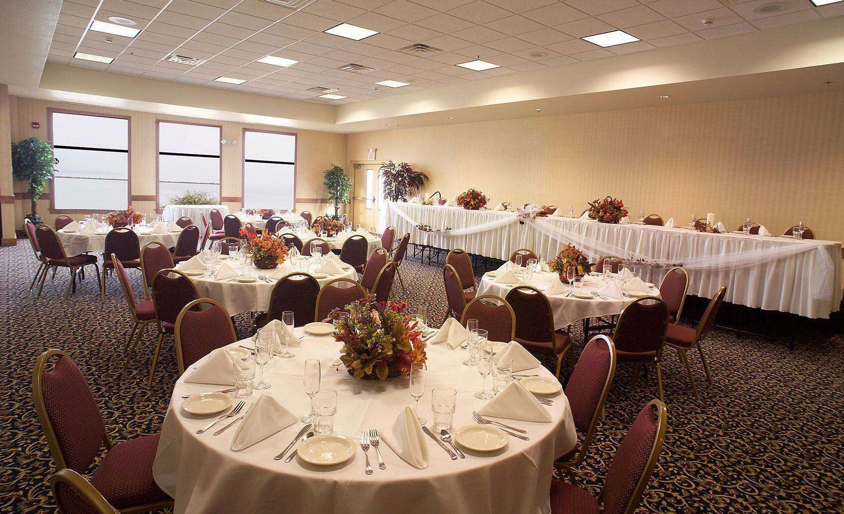 A banquet hall with round tables set for dining, featuring white tablecloths and floral centerpieces.