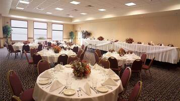 A banquet hall with round tables set for dining, featuring white tablecloths and floral centerpieces.