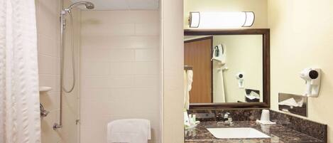 A bathroom with a shower, a sink, a mirror, and a towel rack.