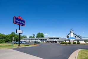 Un hôtel avec une enseigne indiquant « American Inn » et un bâtiment doté d’un toit bleu et d’une cheminée.