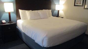 A neatly made bed with white linens, two bedside tables with lamps, and a framed picture on the wall.