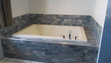 A rectangular bathtub with a tiled surround in a bathroom.