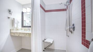 A bathroom with a shower, a toilet, and a sink with a towel rack.