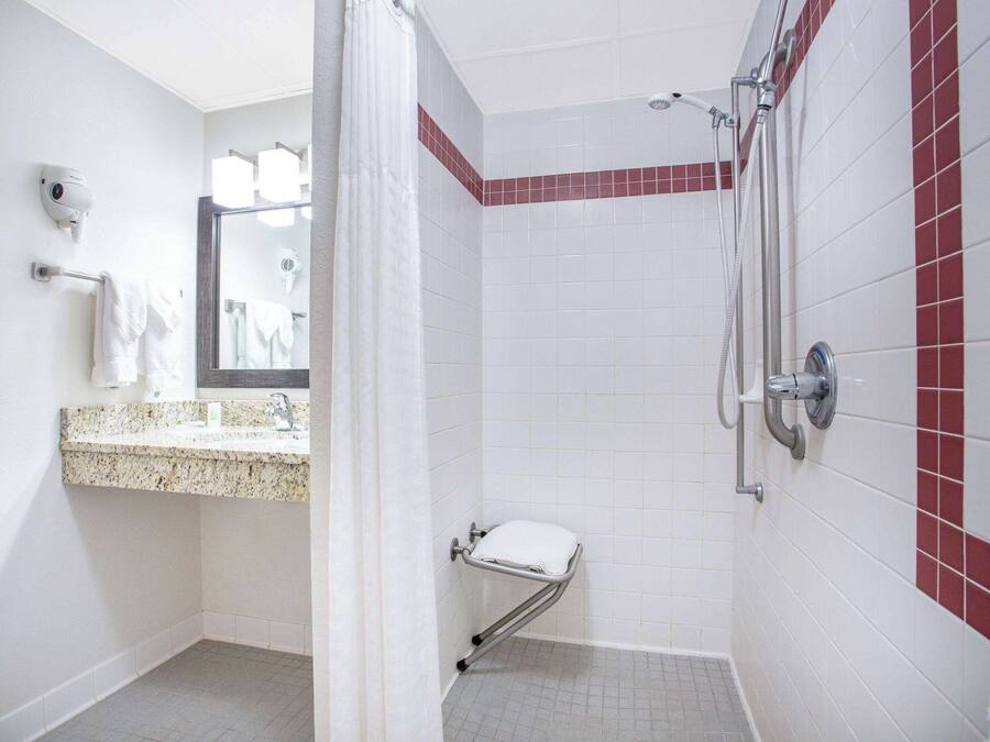 A bathroom with a shower, a toilet, and a sink with a towel rack.