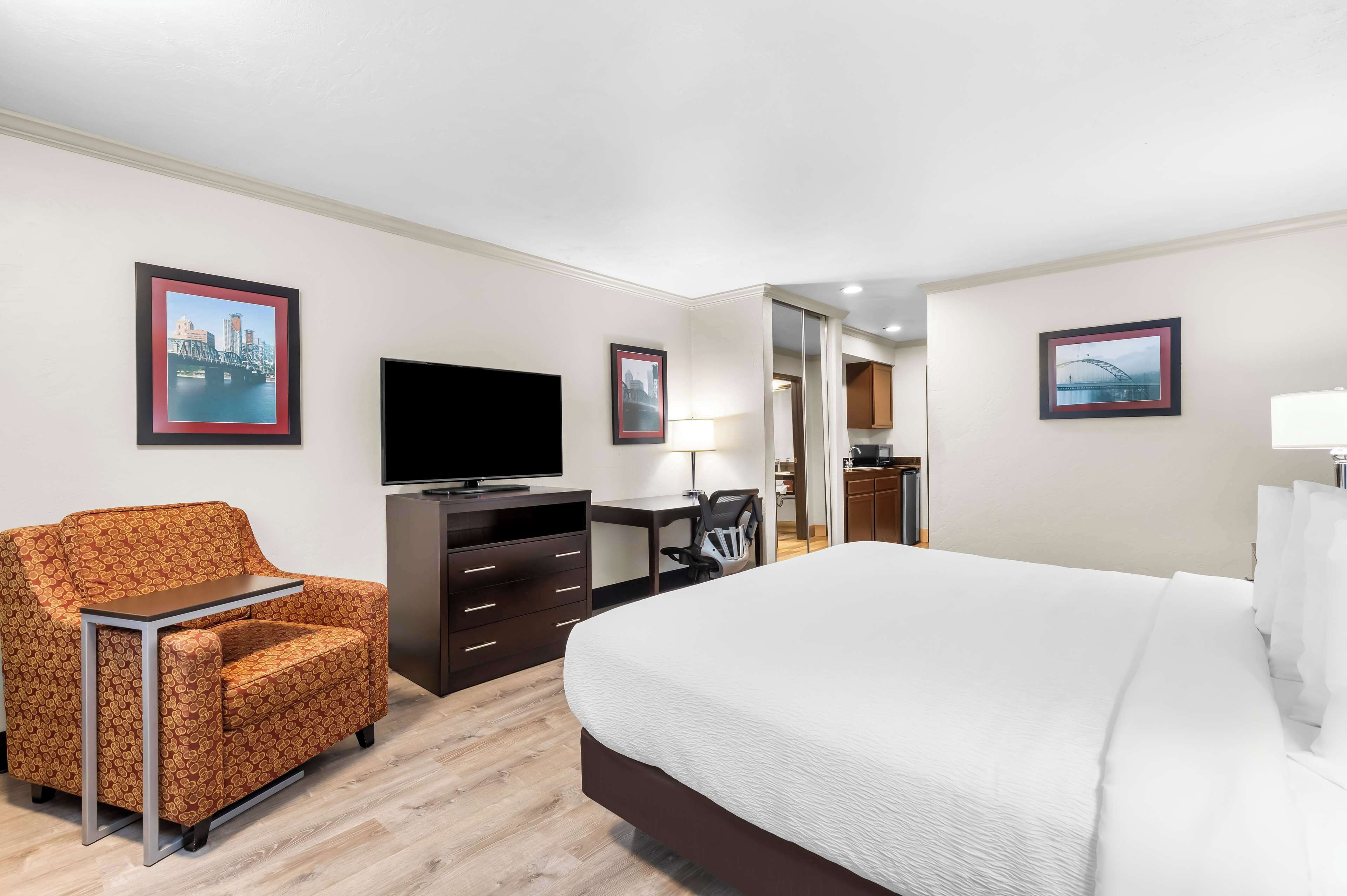 Een hotelkamer met een bed, een bank, een bureau, een televisie en een spiegel.