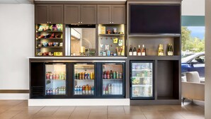 A modern kitchenette with built-in appliances, a flat-screen TV, and a variety of snacks and beverages. - Best Western Plus Parkway Inn (Wilsonville)