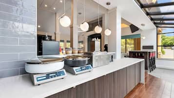 Una cocina moderna con una isla central, luces colgantes y vistas amplias a través de ventanas grandes.
