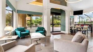 A spacious lobby with a modern design, featuring a seating area with teal and beige chairs, a coffee table, and a flat-screen TV mounted on the wall. - Best Western Plus Parkway Inn (Wilsonville)