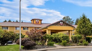 A yellow building with a red roof, a sign indicating it's a Best Western hotel, and a well-maintained garden in front. - Best Western Plus Parkway Inn (Wilsonville)