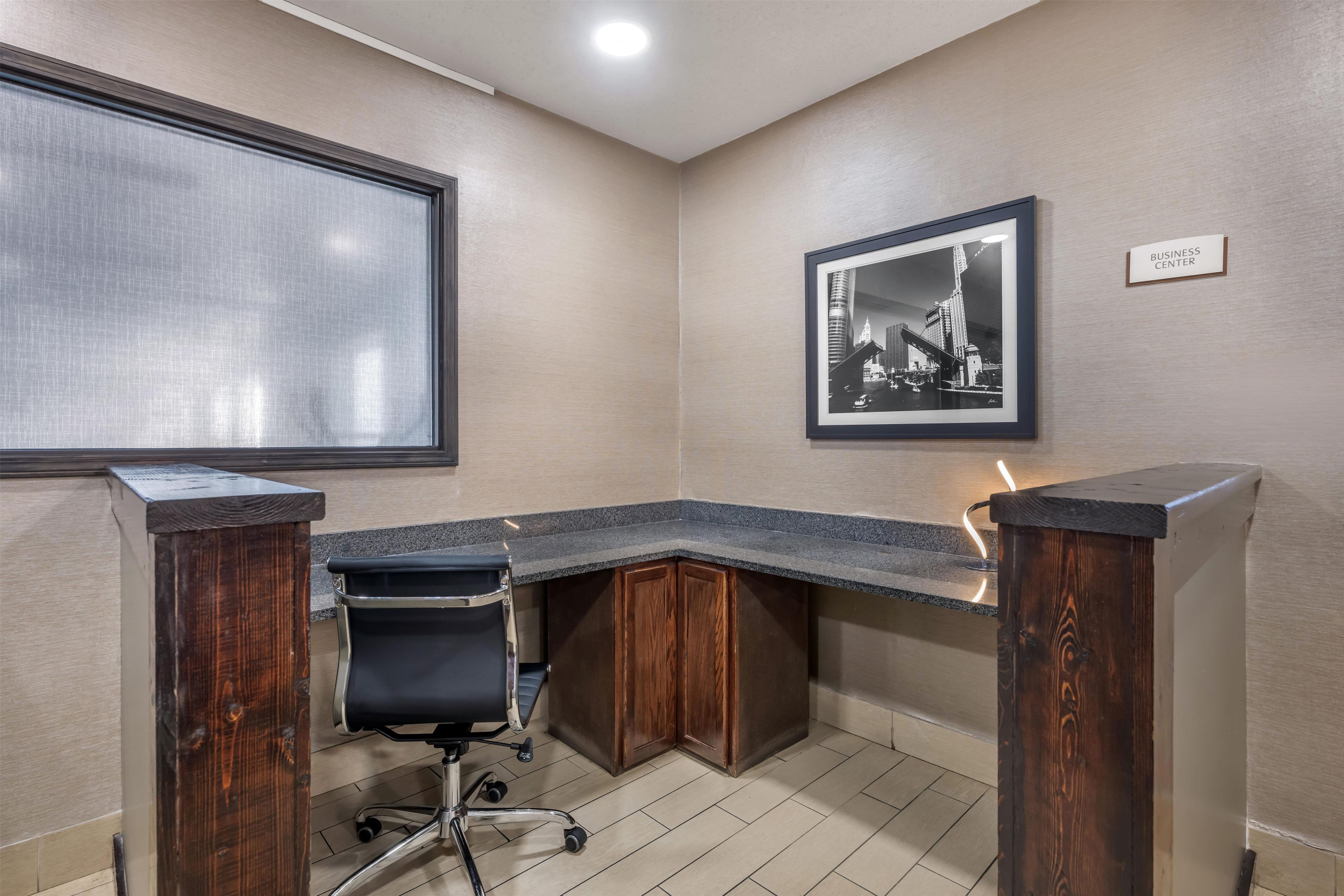 A corner office with a desk, chair, and a framed picture on the wall.
