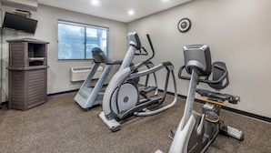 A gym with treadmills, an elliptical, and a stationary bike, a TV, and a clock on the wall. - Best Western Des Plaines/O’Hare (Des Plaines)