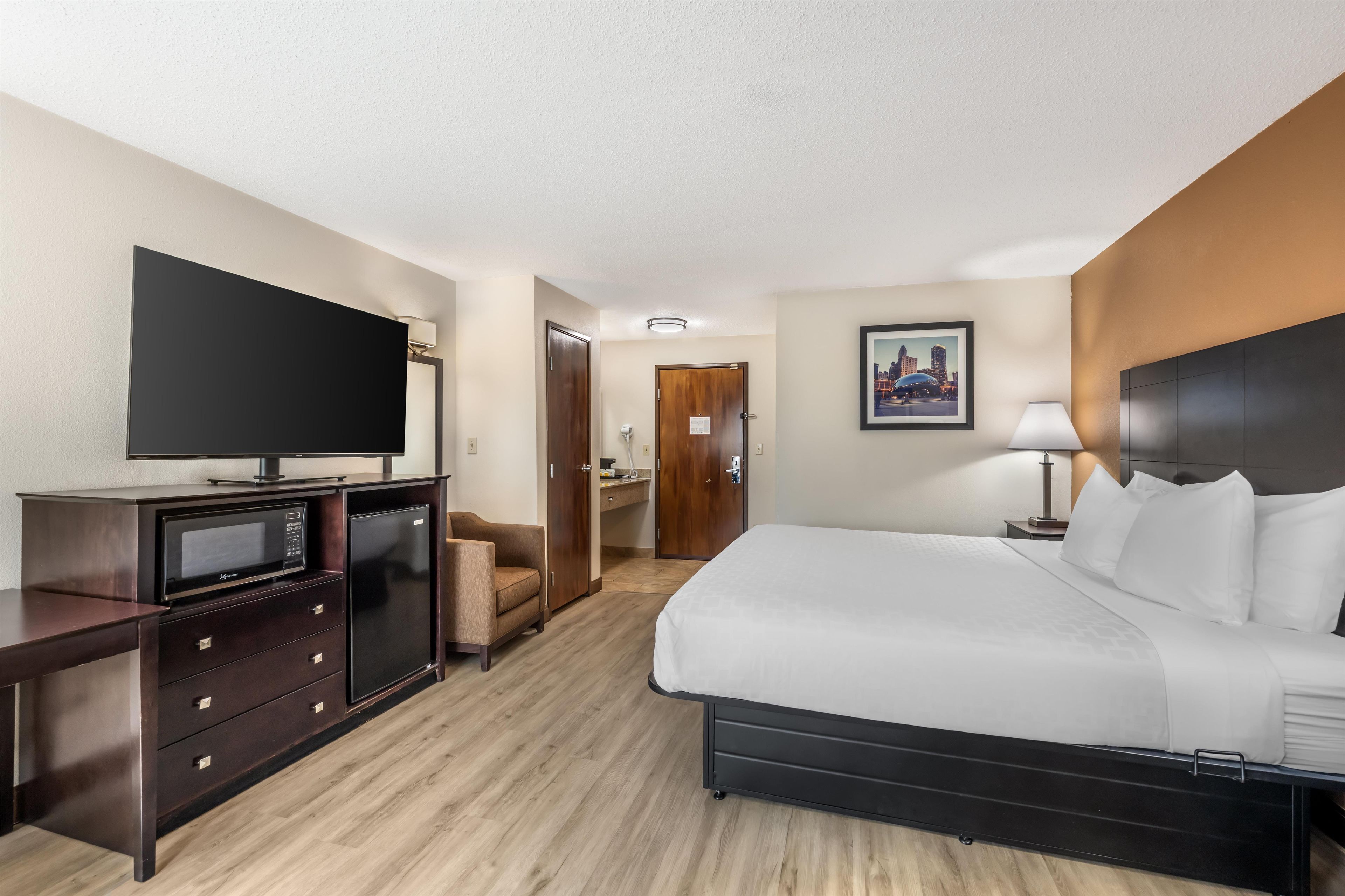 Une chambre d’hôtel équipée d’un lit, d’une télévision, d’un bureau avec un micro-ondes, d’une chaise et d’une porte donnant accès à une salle de bain.