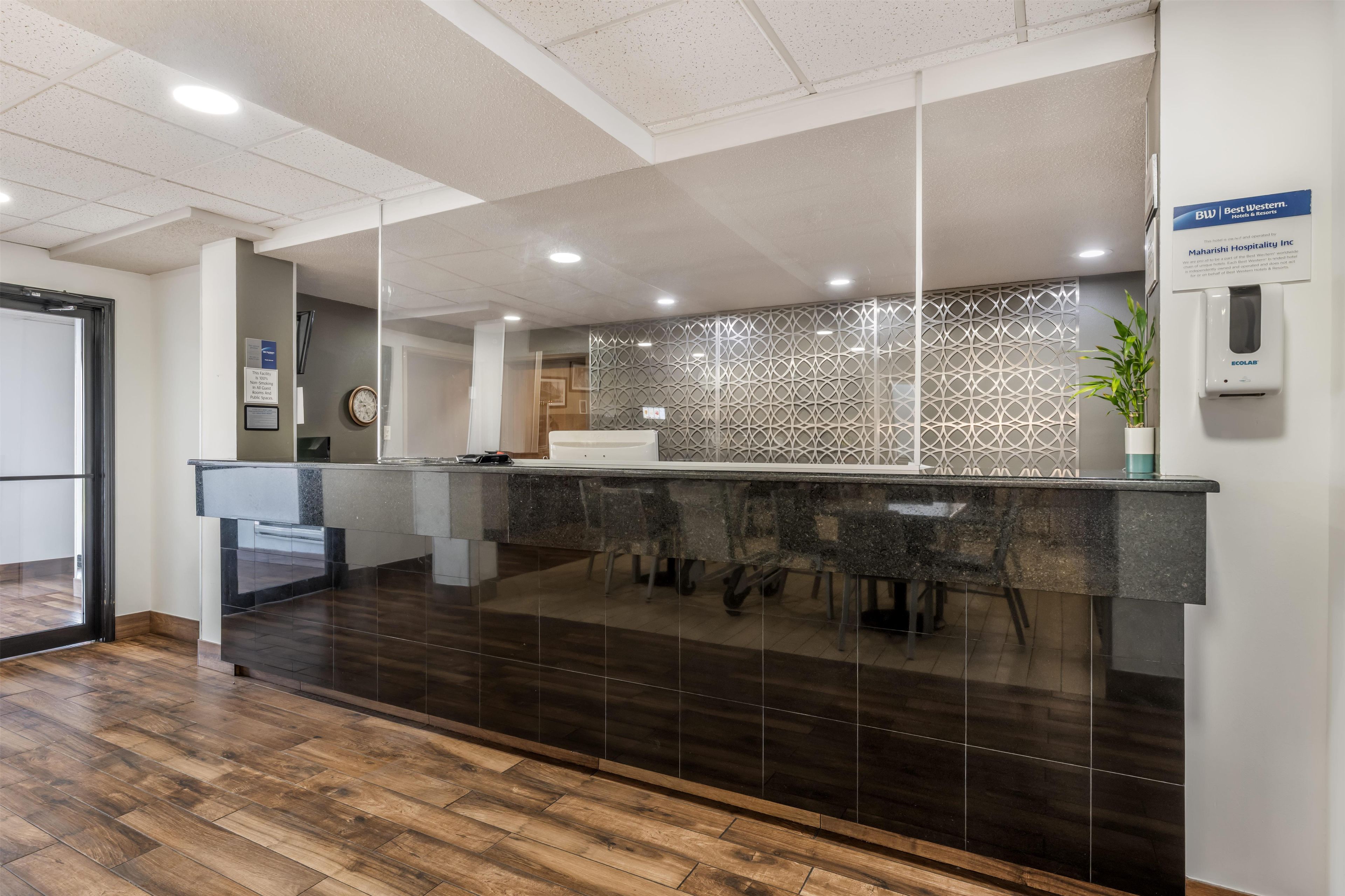 A reception area with a modern design, featuring a reception desk, a clock, and a plant.