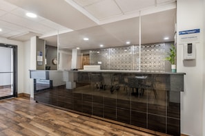 A reception area with a modern design, featuring a reception desk, a clock, and a plant. - Best Western Des Plaines/O’Hare (Des Plaines)