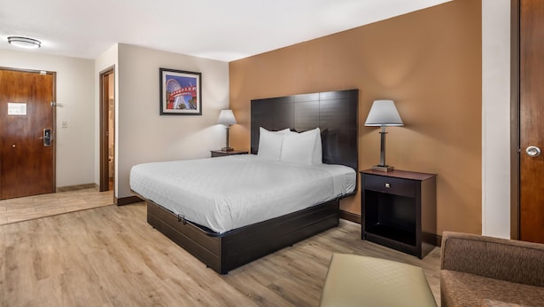 A hotel room with a large bed, two bedside tables, a chair, and a wall-mounted picture. - Best Western Des Plaines/O’Hare (Des Plaines)
