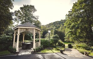A gazebo with intricate carvings, surrounded by lush greenery and a stone pathway. - Best Western Valley Hotel (Telford)