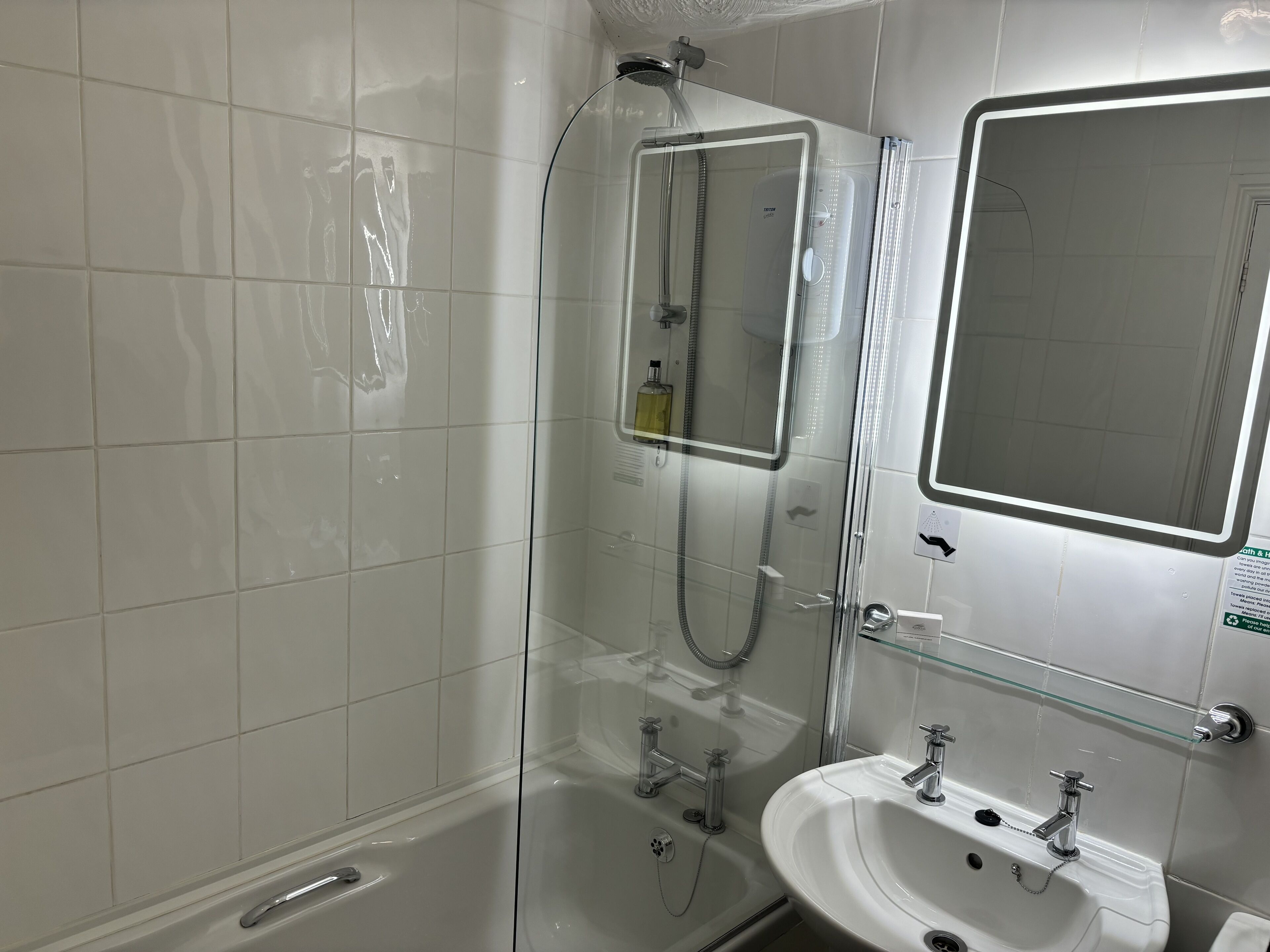 Une salle de bain moderne avec une douche à parois de verre, un lavabo blanc et un miroir.
