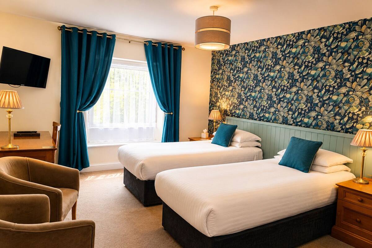 A hotel room with two beds, a TV, a desk, and a chair.