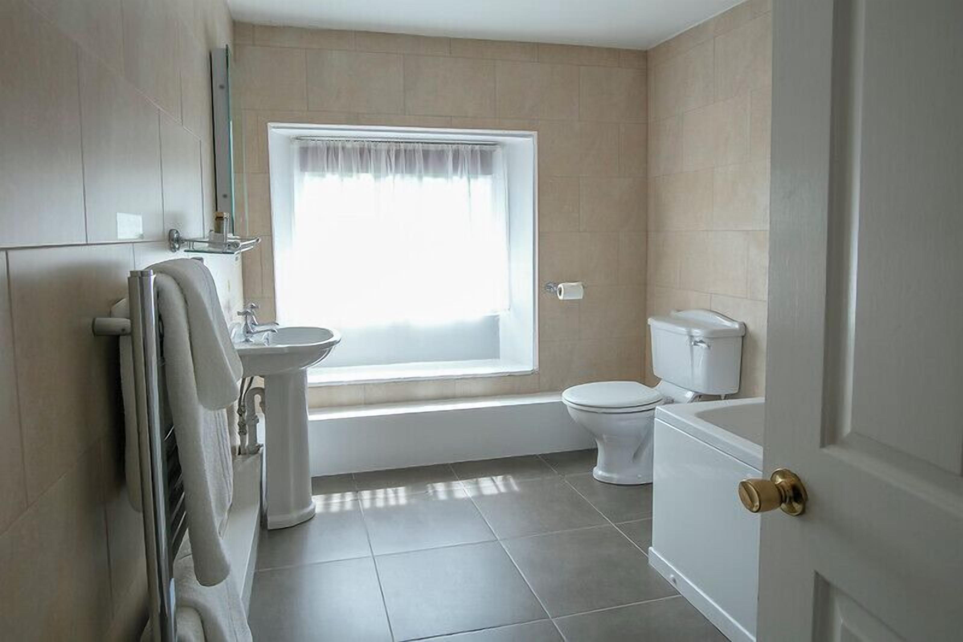A modern bathroom with a bathtub, toilet, and sink.