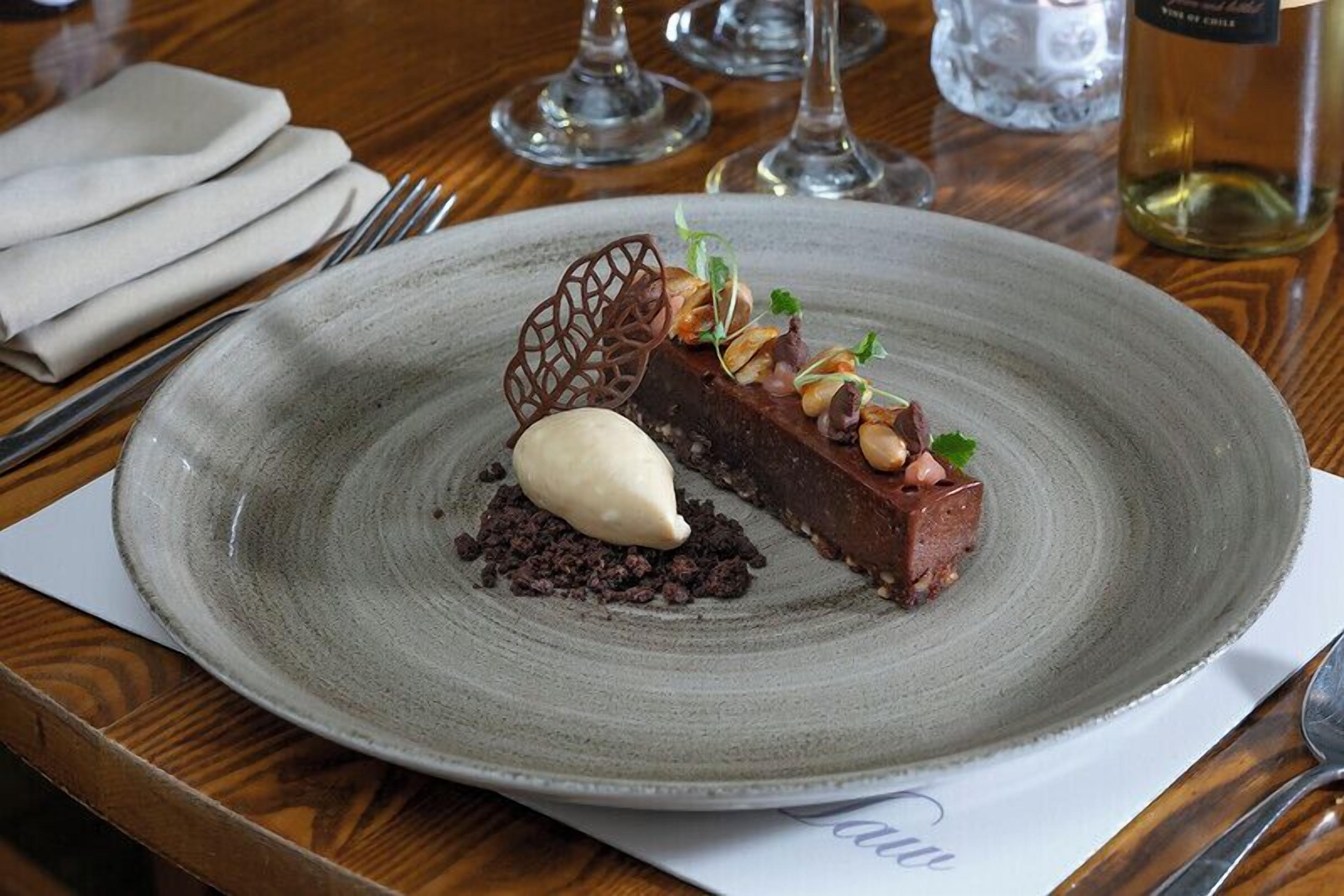 A dessert plate with a chocolate cake, a scoop of ice cream, and garnishes on a ceramic plate.