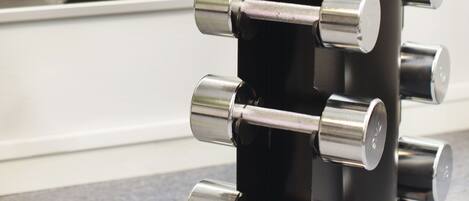 Un soporte vertical negro para mancuernas con varias pesas.