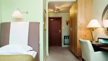 A hotel room with a bed, a desk, a chair, a wardrobe, and a bathroom door.