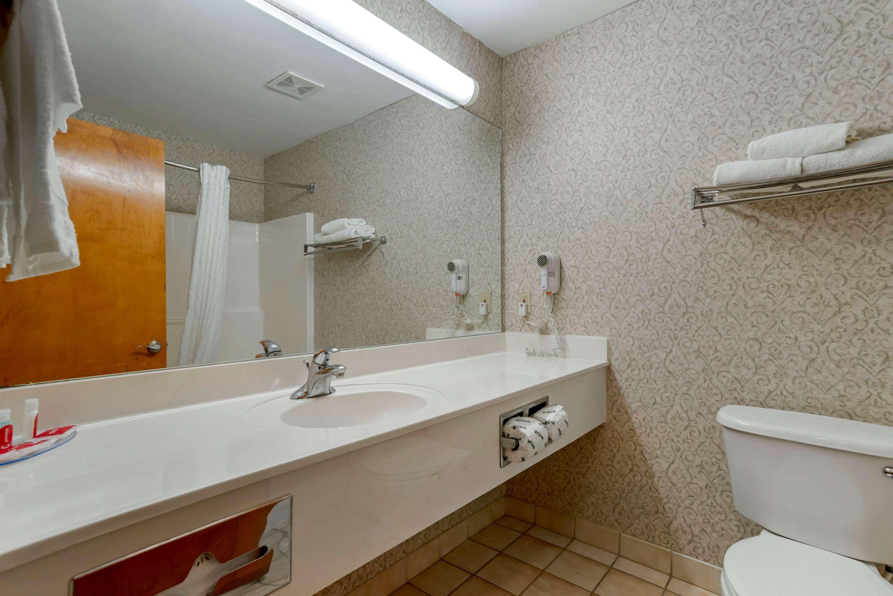 A bathroom with a white sink, mirror, towel rack, and toilet.