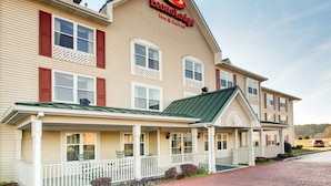 Kaksikerroksinen Econolodge Inn & Suites -hotelli, jossa on vihreä katto, valkoinen kuisti ja punaiset ikkunaluukut.