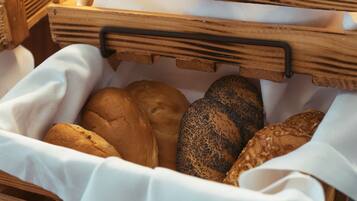 Ein Weidenkorb mit verschiedenen Brotsorten, darunter ein Mohnbrötchen, ein einfaches Brötchen und ein Körnerbrötchen.