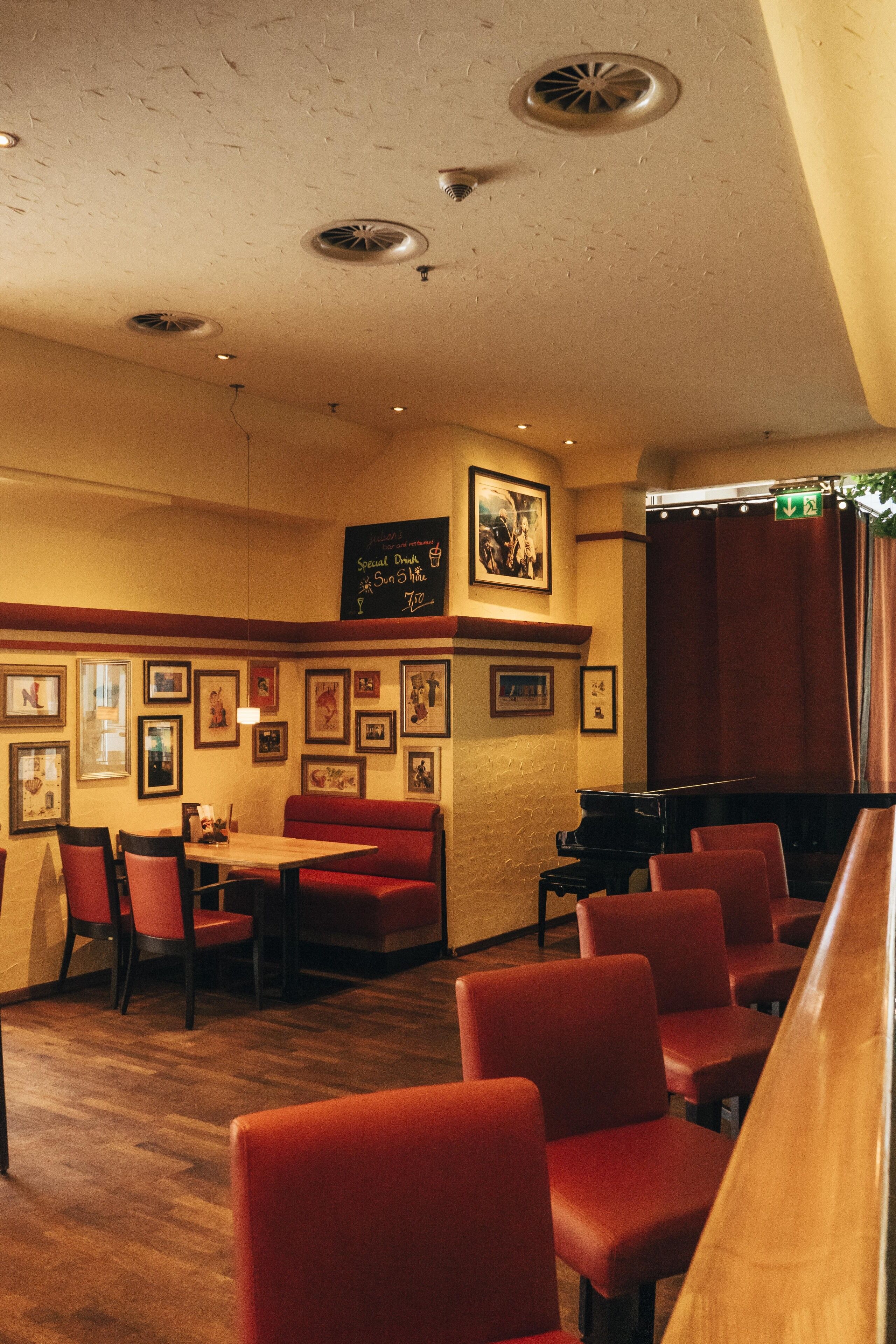 Un restaurante con asientos rojos tipo cabina y un piano.