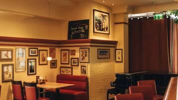 Un restaurante con asientos rojos tipo cabina y un piano.