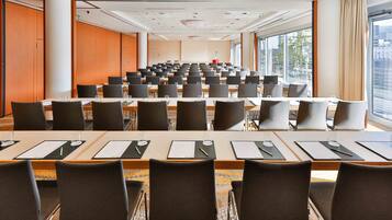 Une salle de conférence dotée de plusieurs tables et chaises, de grandes fenêtres et offrant une vue sur la ville.