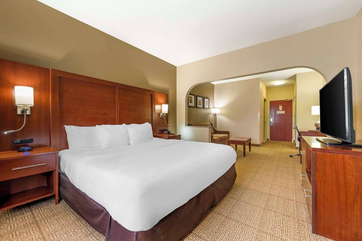 Una habitación de hotel con una cama grande, un escritorio, un televisor y una lámpara de escritorio.