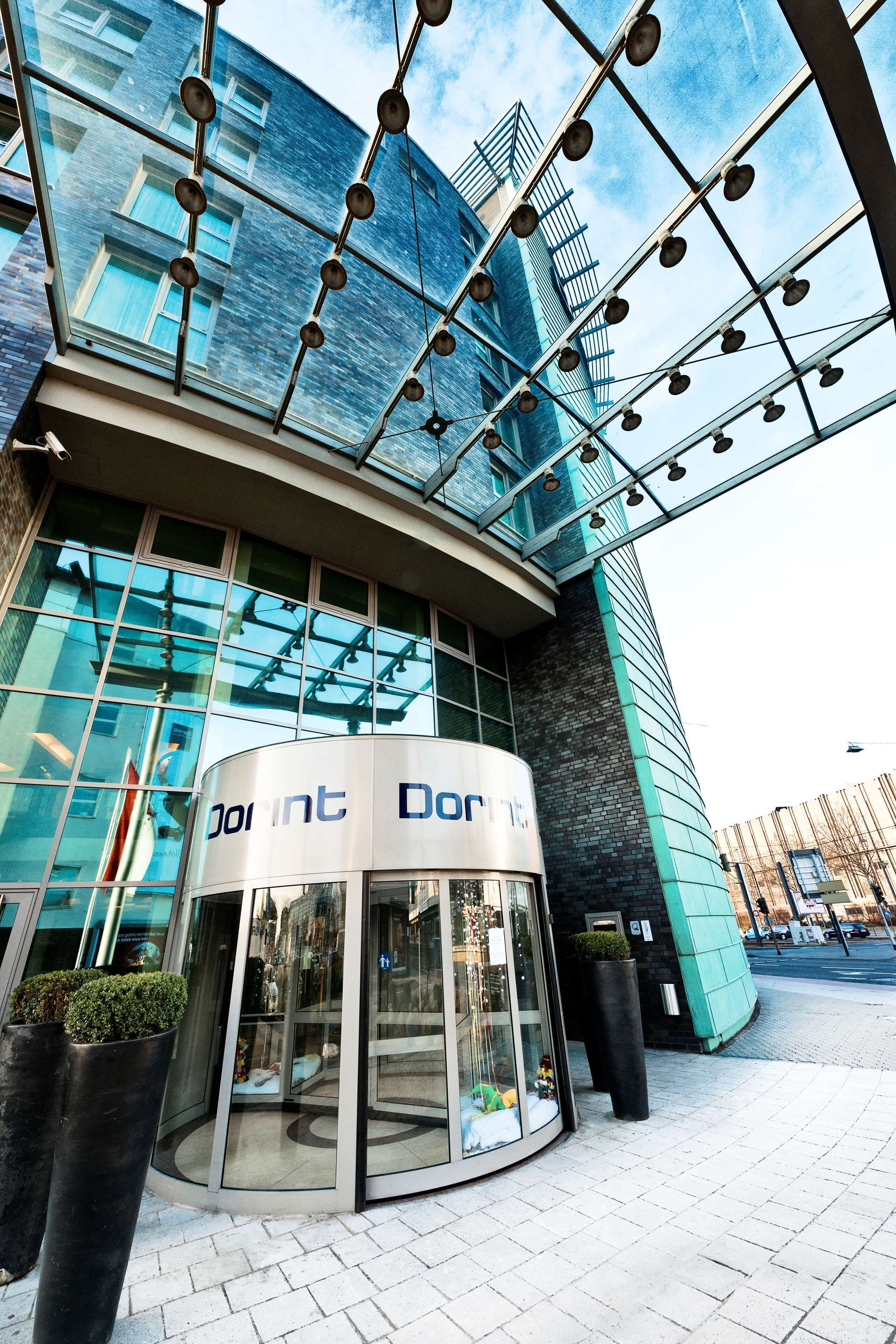 A modern hotel entrance with a glass revolving door and a clear view of the building's exterior.