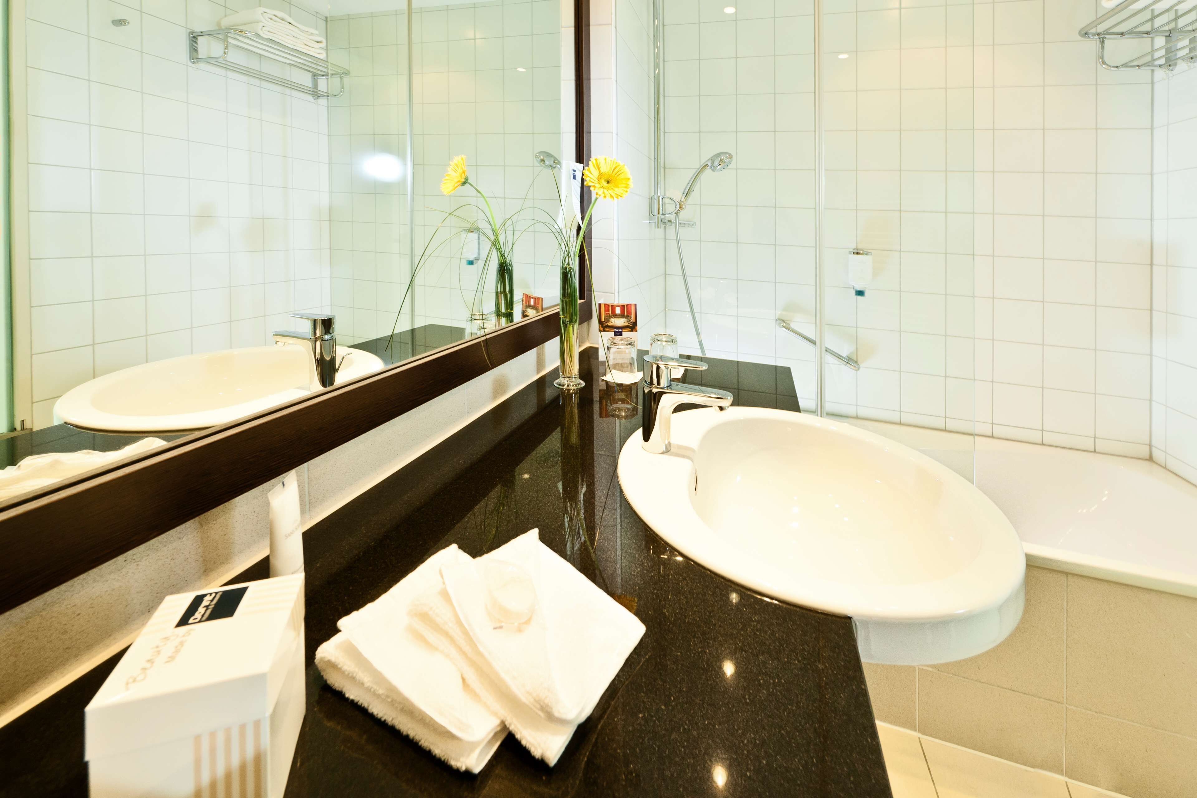 A bathroom with two sinks, a mirror, and a bathtub.