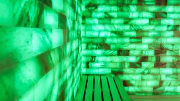 Een kamer met een wand in groen licht en een houten bank.