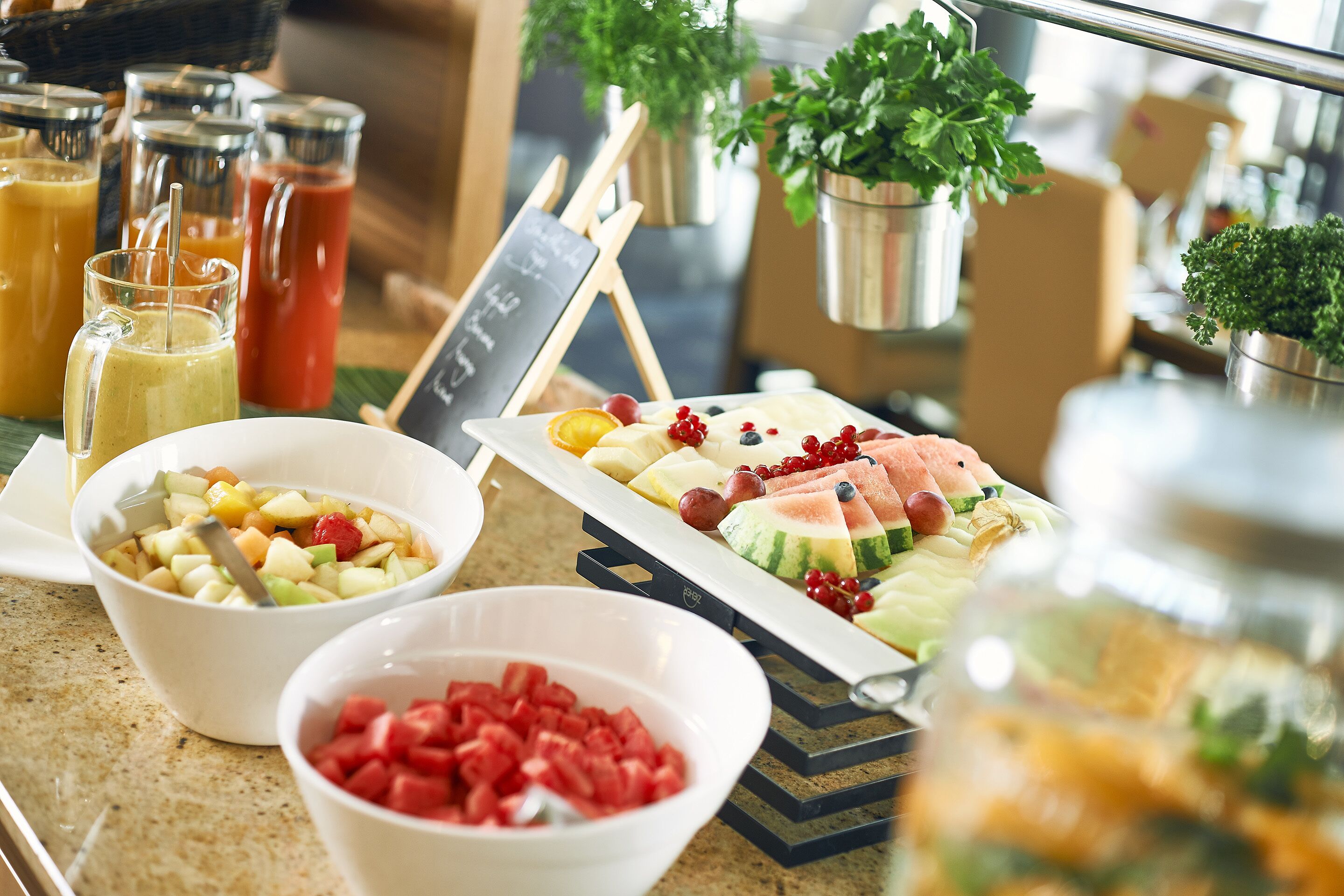 A buffet table with various fruits, a sign, and a chalkboard.